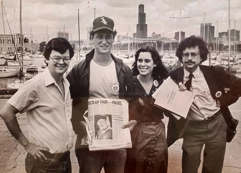 Thom Clark, Lew Kreinberg, Kathy Tholin & Scott Bernstein posing with newspaper showing world's fair canceled in front of Chicago skyline. Photo courtesy Kathy Tholin